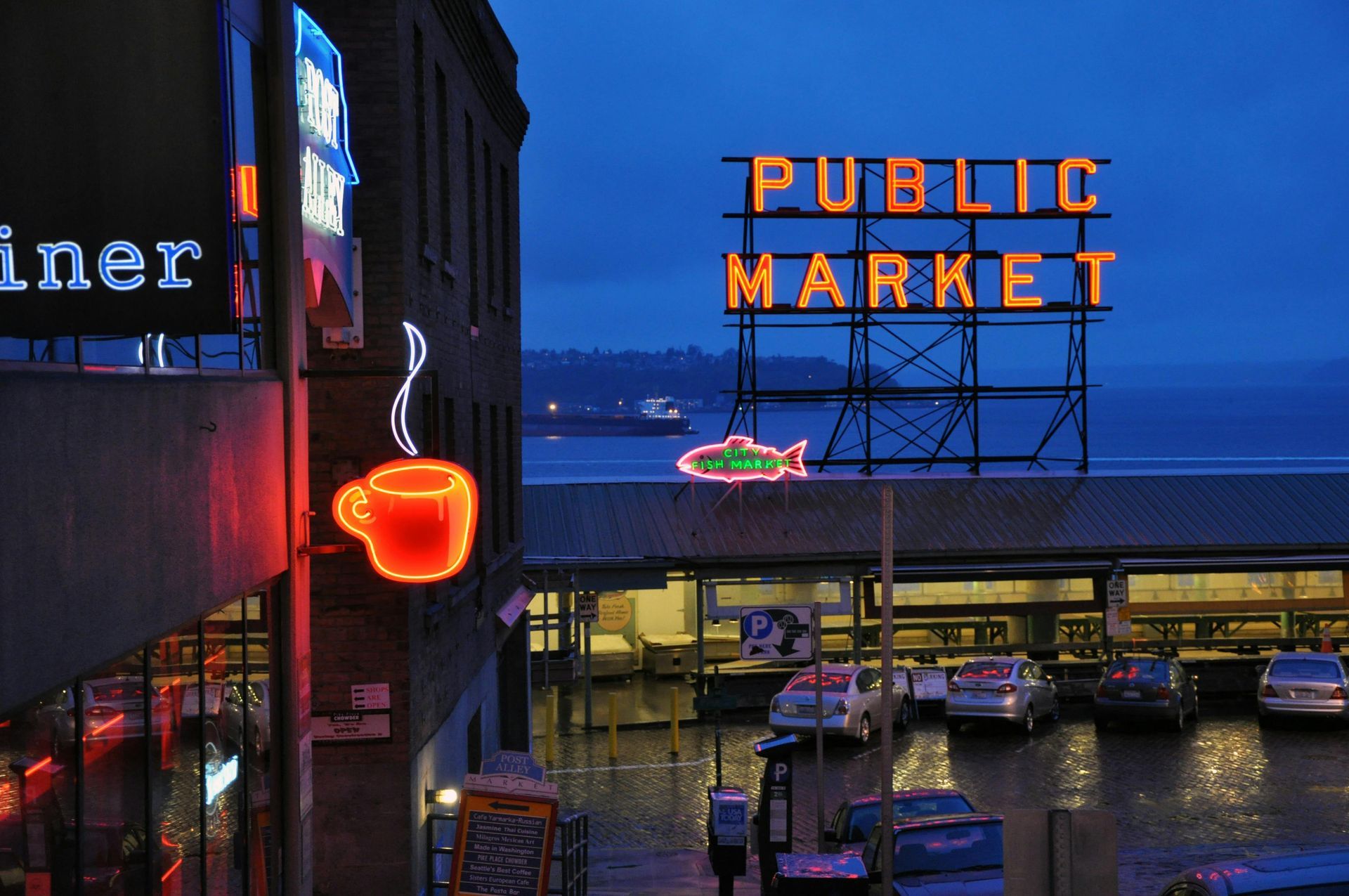 Neon signs illuminate Seattle's Pike Place Market at dusk: