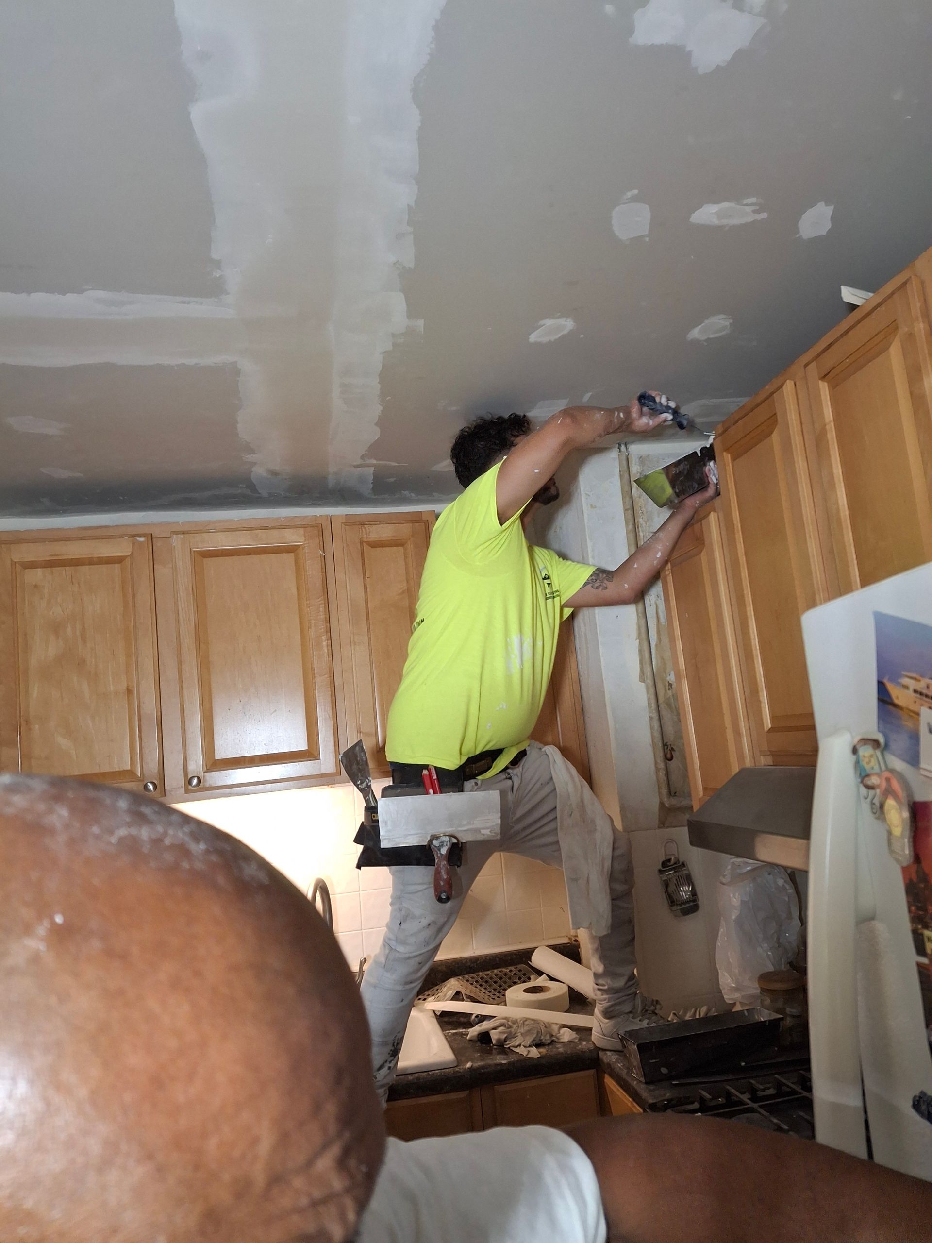 A man in a yellow shirt is working in a kitchen