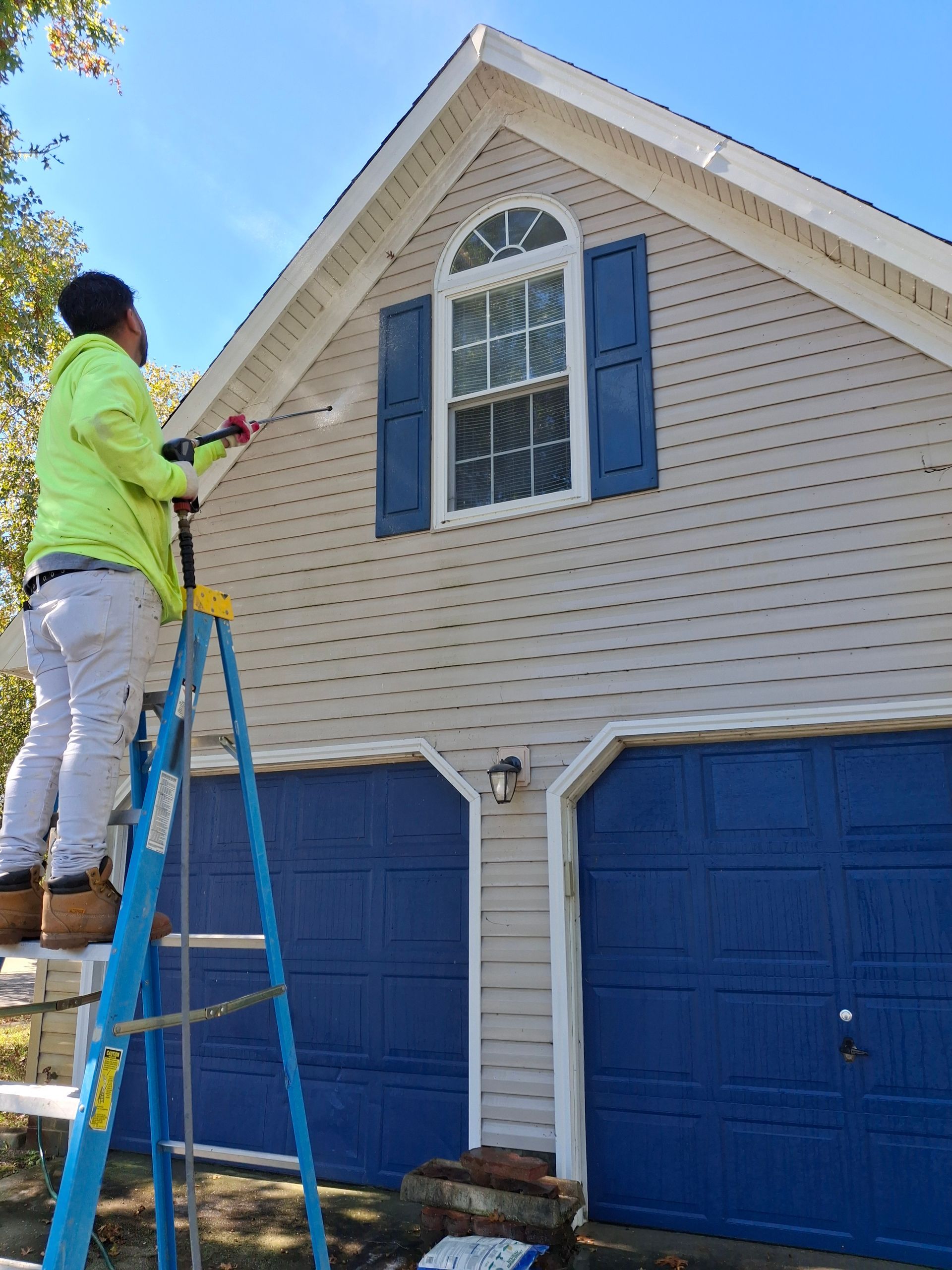 A man is standing on a ladder painting a house.