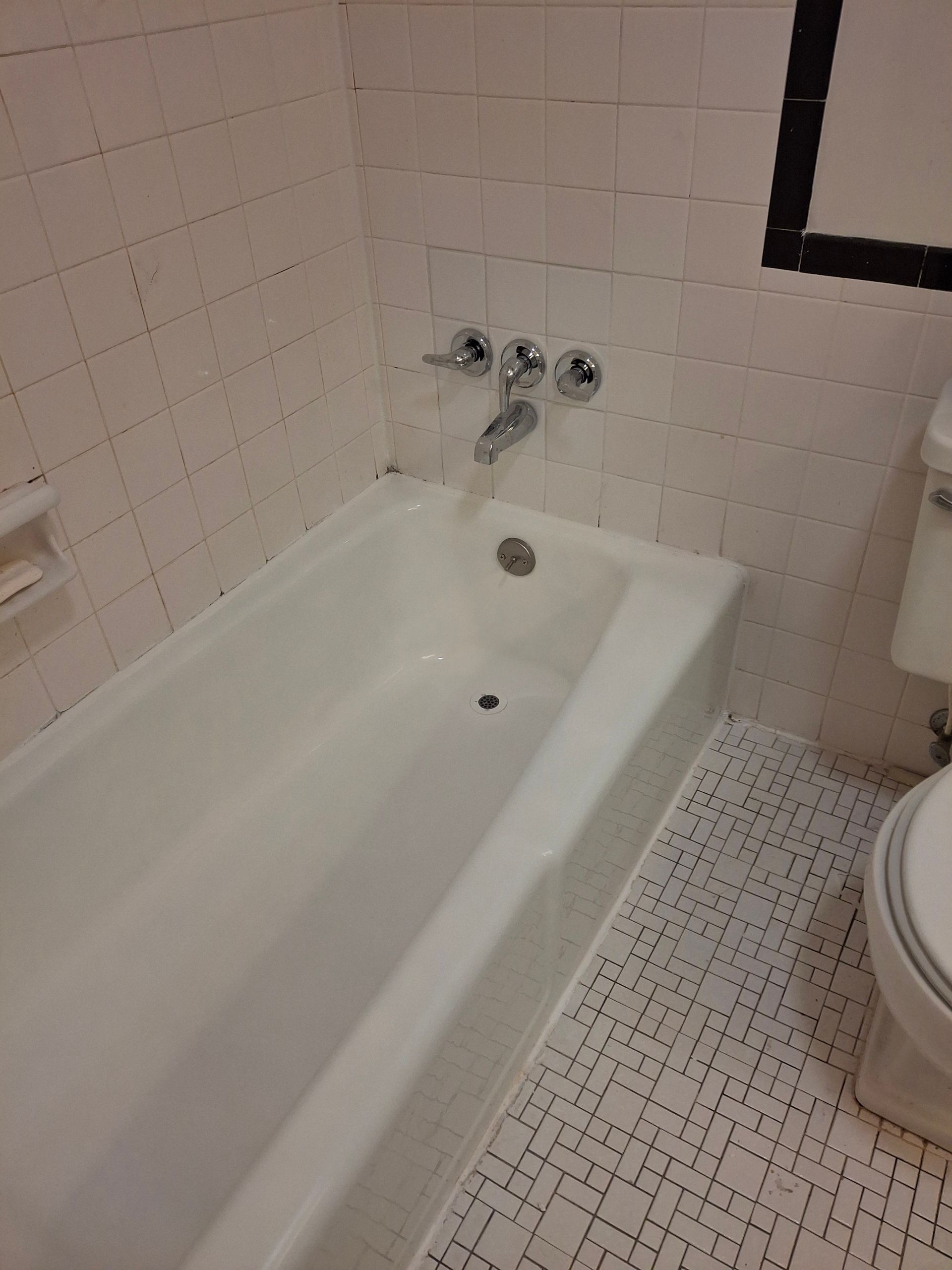 A bathroom with a bathtub , toilet and mirror.