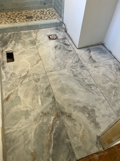 A bathroom with a tiled floor and a shower stall.