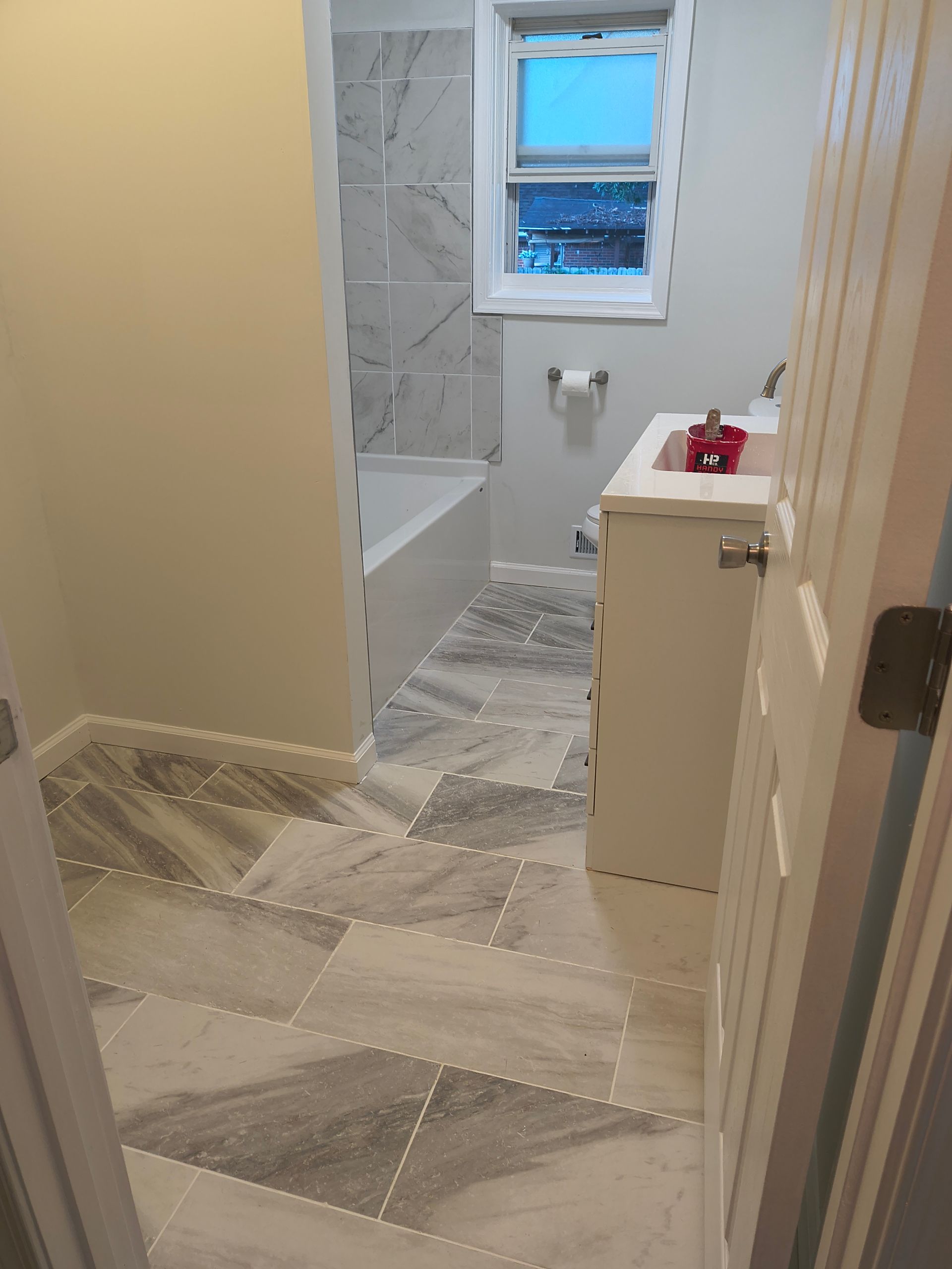 Bathroom under renovation with taped floor, white vanity, and window above a toilet.