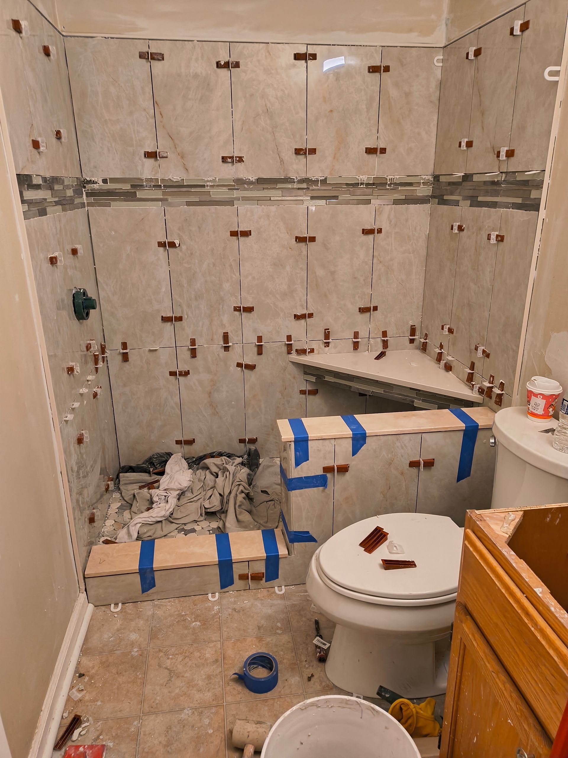 Partially tiled bathroom under renovation with exposed walls, toilet, and construction debris on the floor