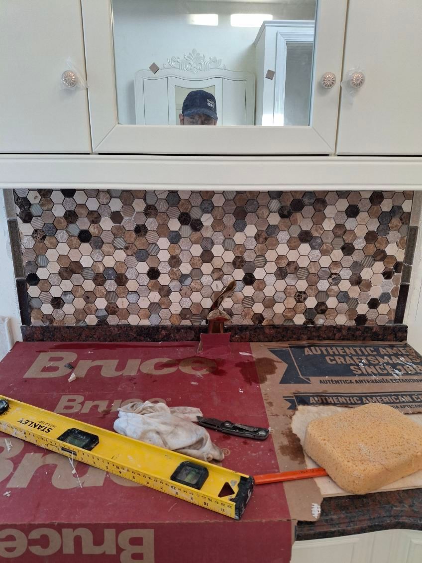 A box of bruce tile is sitting on a counter next to a level and a sponge.