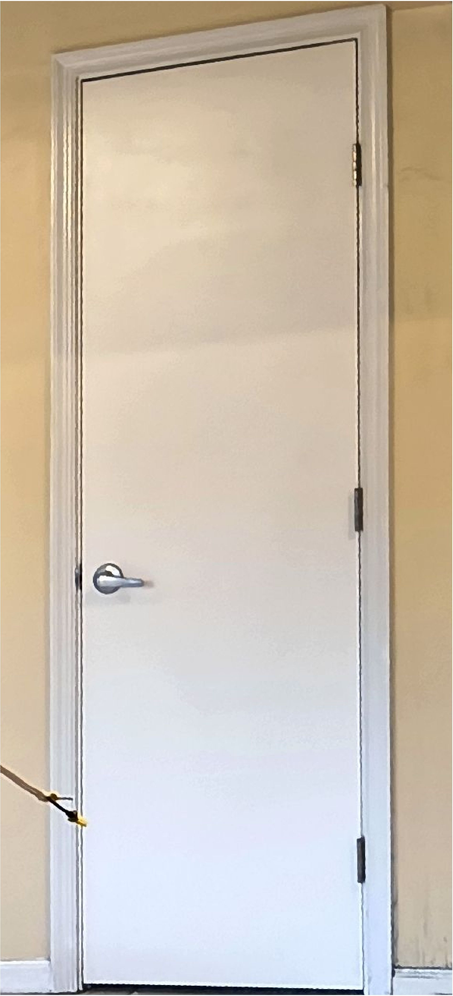 White interior door with silver handle in a beige hallway
