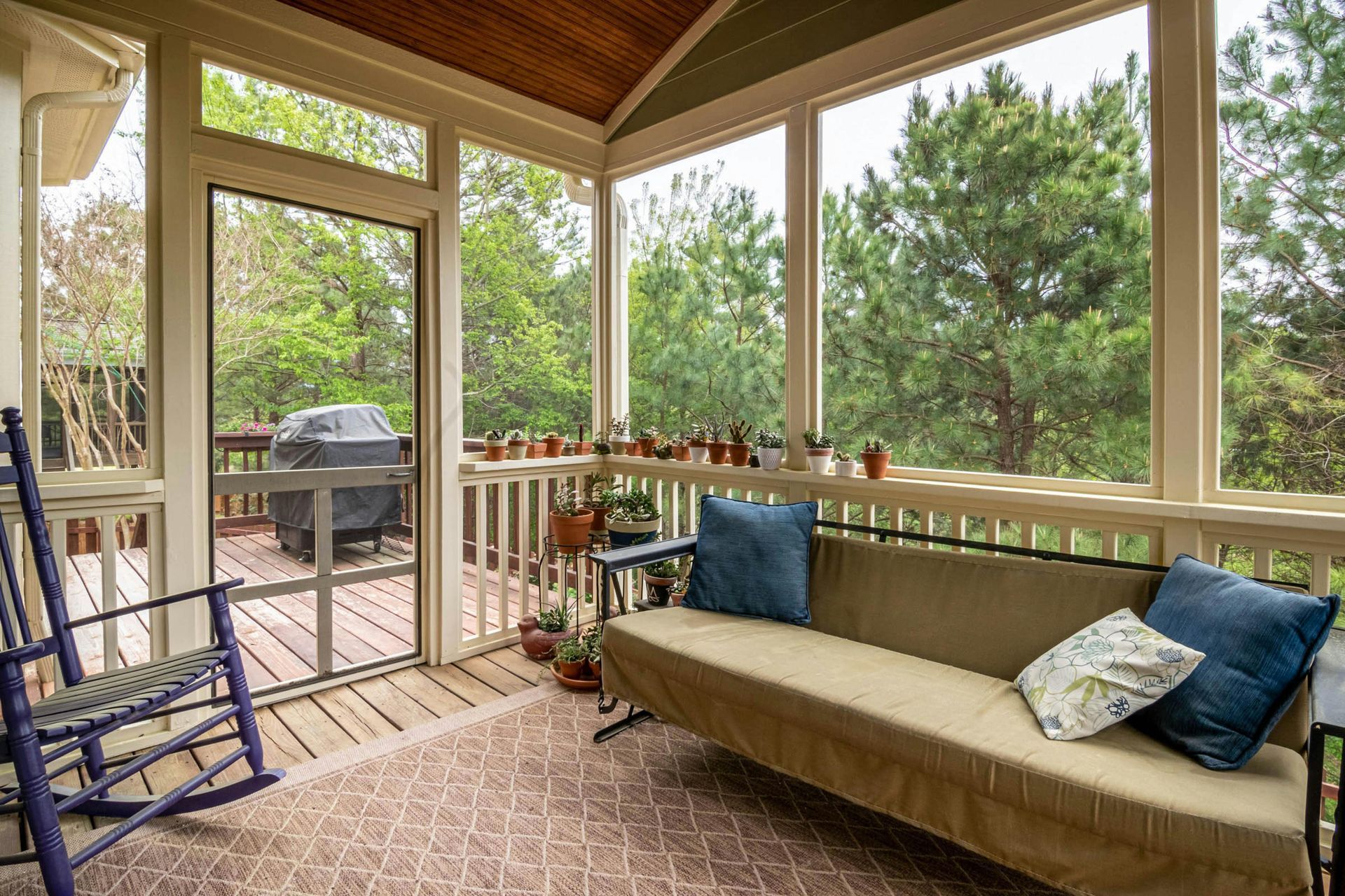 Wooden backyard deck with stairs beside a house and fenced yard