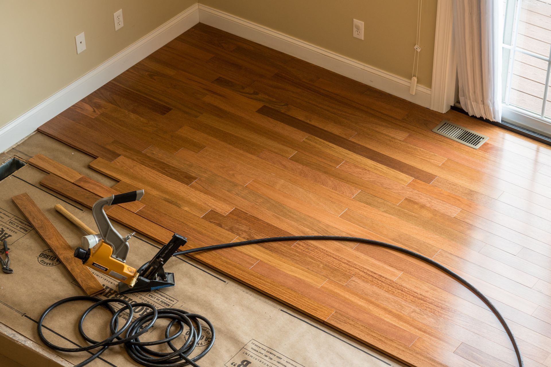 A wooden floor is being installed in a living room.