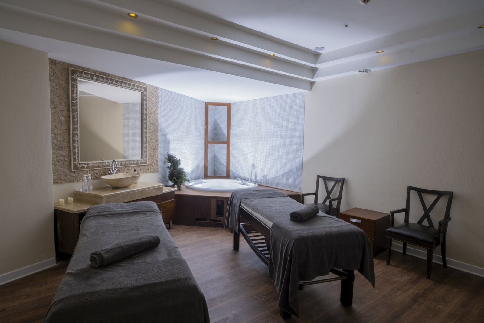 Iki masaj masası ve jakuzi bulunan bir spa odası.
