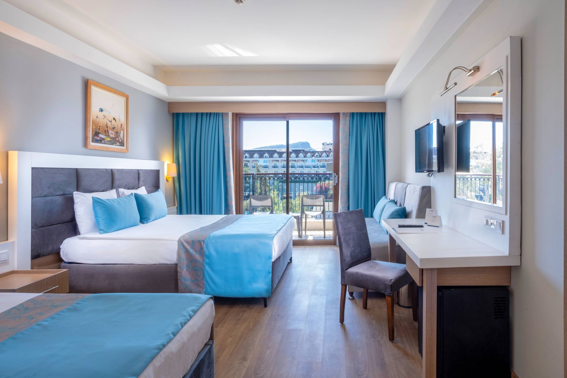 Гостиничный номер с двумя кроватями, письменным столом и телевизором.