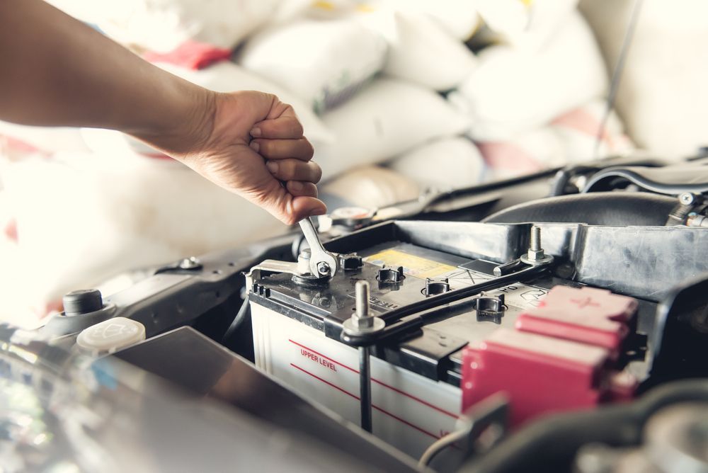 A Person Is Fixing A Car Battery With A Wrench — Auto Spares Morisset In Morisset, NSW