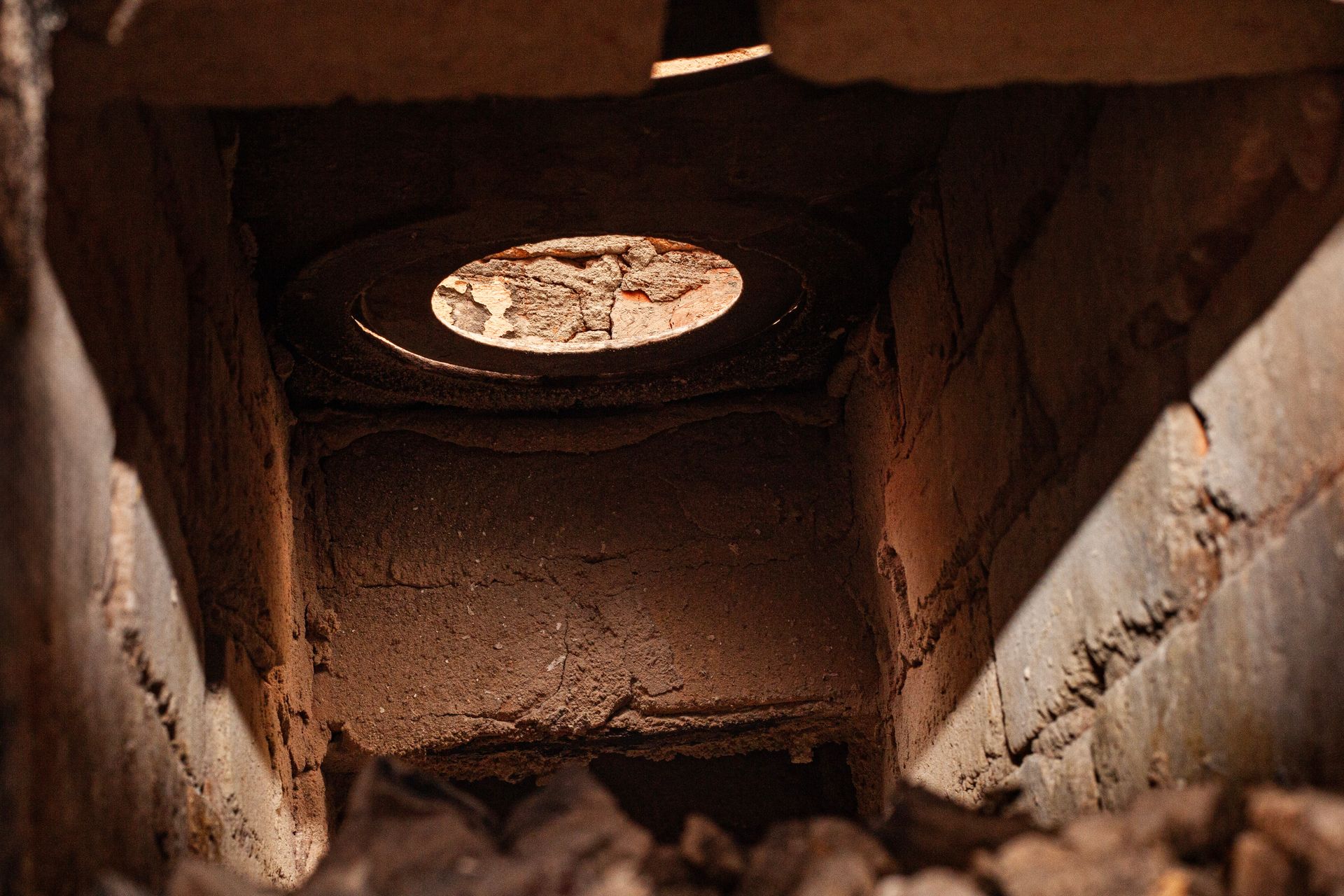 Soot-covered firebox interior with light shining down the open chimney flue.