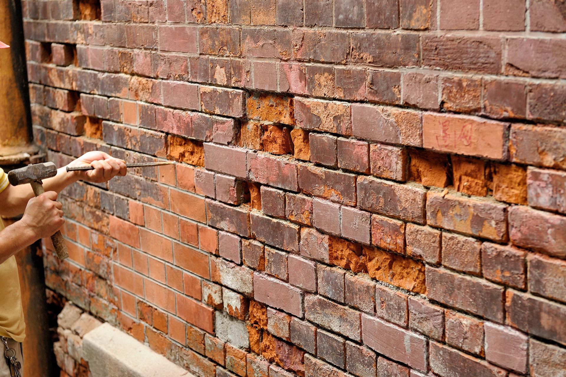 A man is repairing a brick wall. A man is repairing a brick wall.