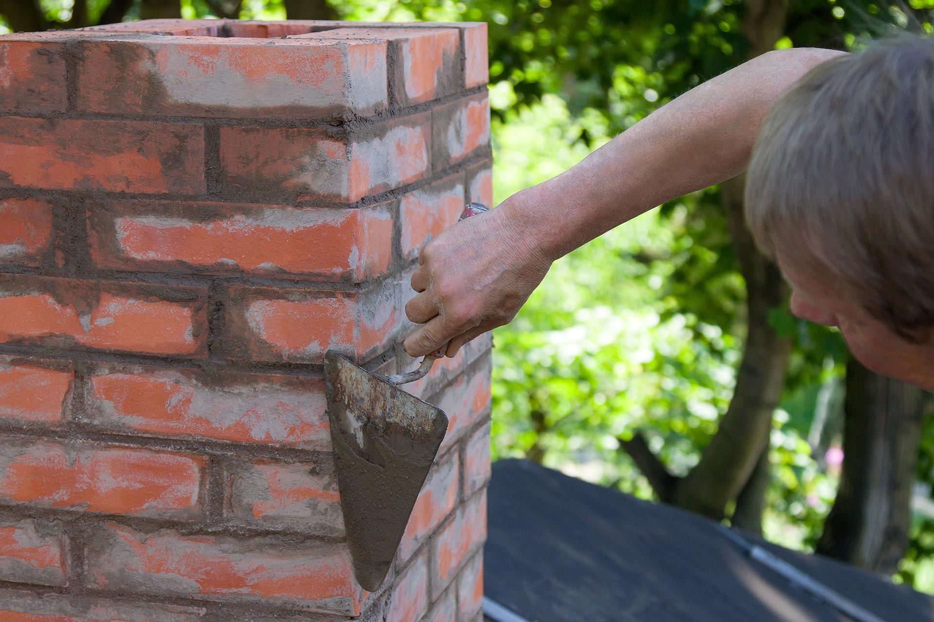A man is doing masonry work on a chimney.