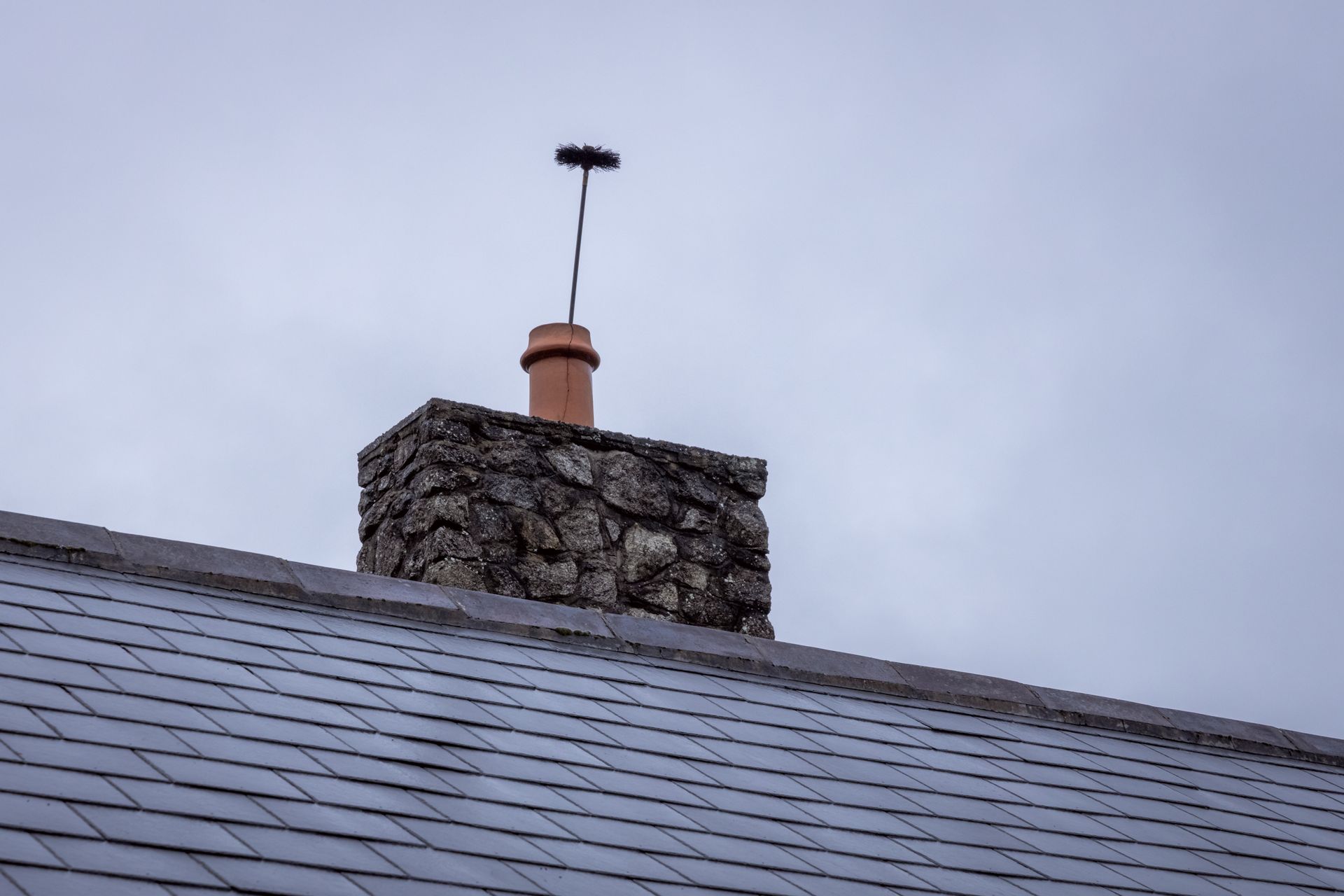 House with a tiled roof and chimney in a quiet suburban setting under a cloudy sky House with a tiled roof and chimney in a quiet suburban setting under a cloudy sky
