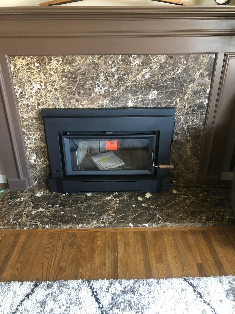 Fireplace with black frame inset in marble and wood trim.
