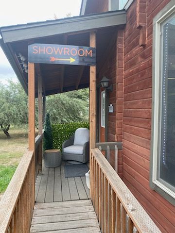 Showroom sign with arrow points right. Porch with chair, wood railing, and red building.