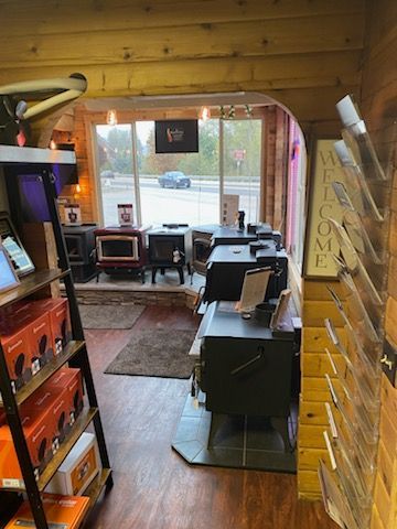 Interior of a wood stove showroom, showcasing various stove models with brochures and accessories.