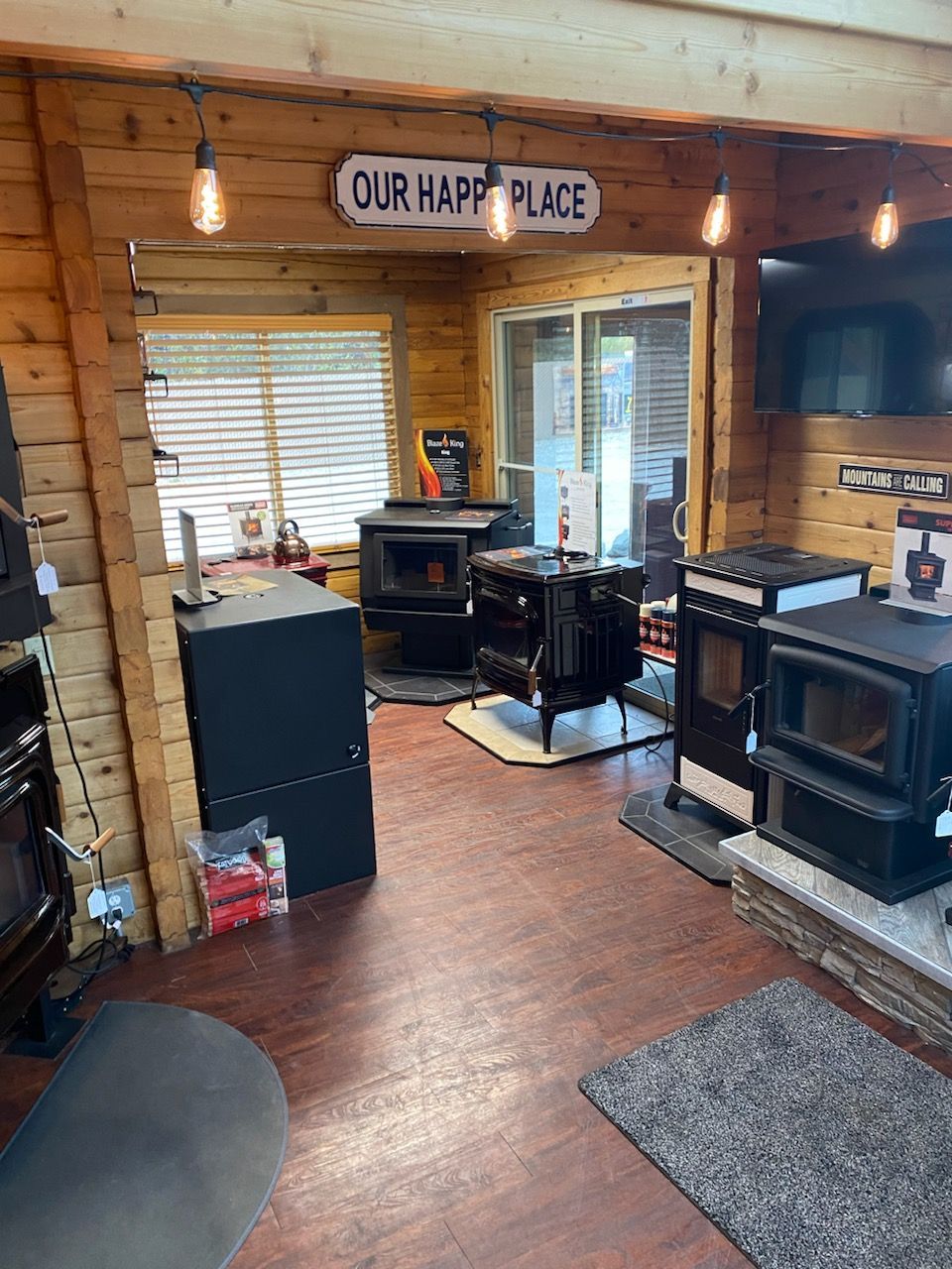 Interior of a shop displaying multiple wood-burning stoves and a sign that reads 