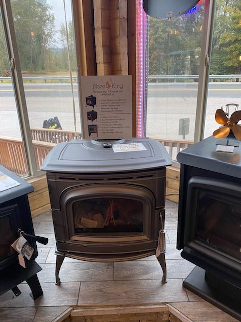 A dark gray wood stove with a glass door in a showroom.