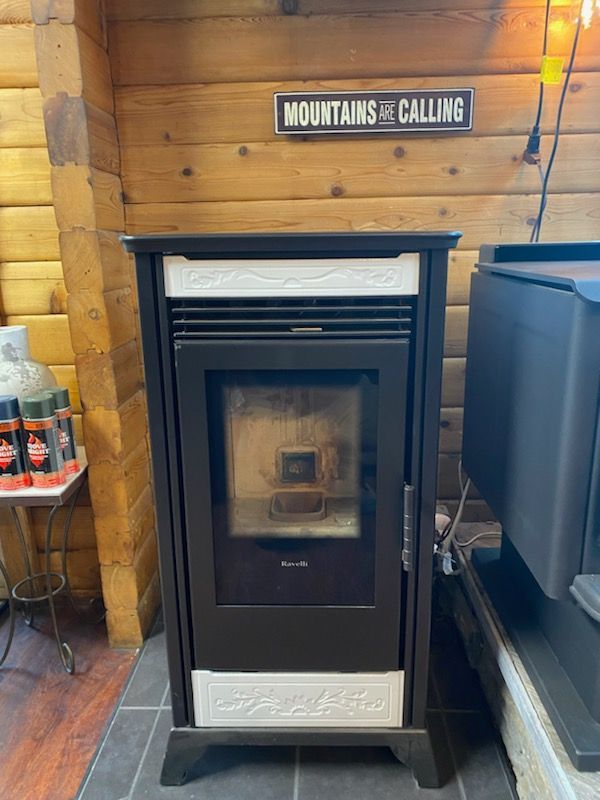 Black pellet stove with cream accents against wood paneling, 