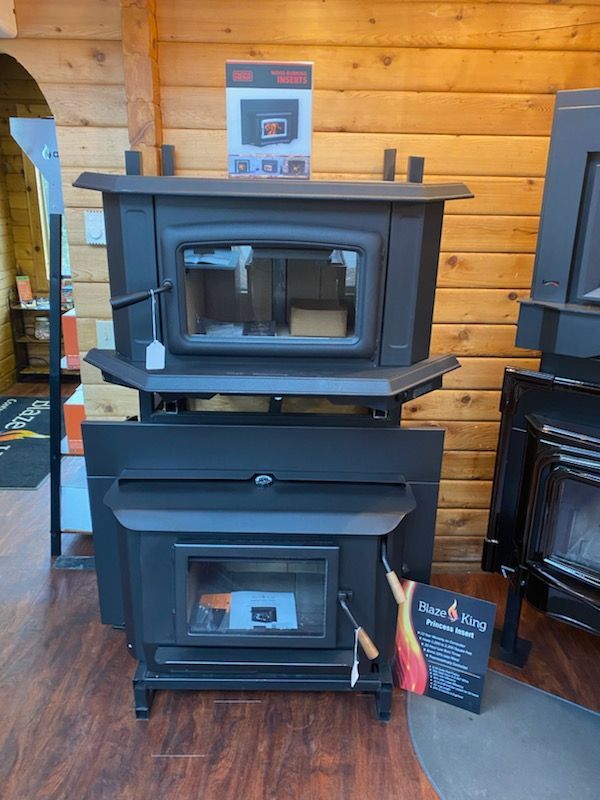 Two black pellet stoves on display in a wood-paneled showroom.