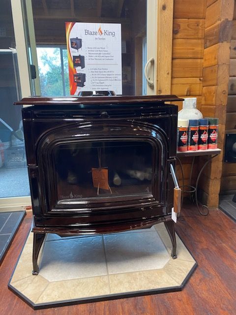 Dark wood-paneled wood stove on a tiled hearth, with a sign in the background.