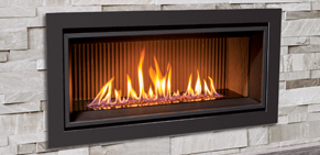 Modern black gas fireplace set into a stone wall with bright orange flames