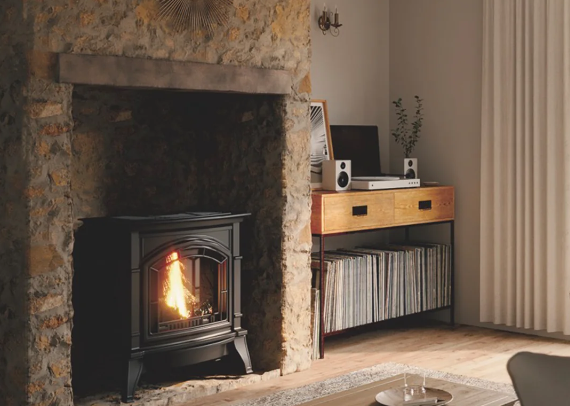 Cozy living room with a lit fireplace, stone surround, and a wooden shelf with records and speakers
