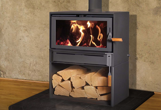 Black wood-burning stove with visible flames and stacked logs in a lower storage compartment indoors