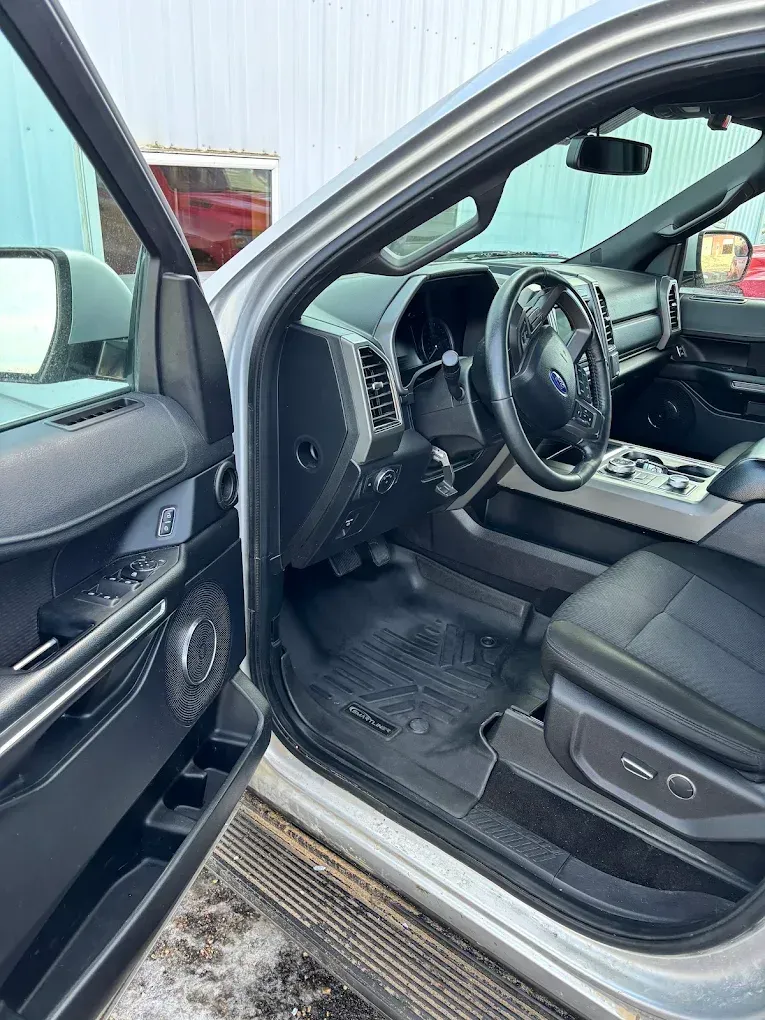 Damaged car interior with shattered steering wheel and opened driver’s door, showing airbag deployment