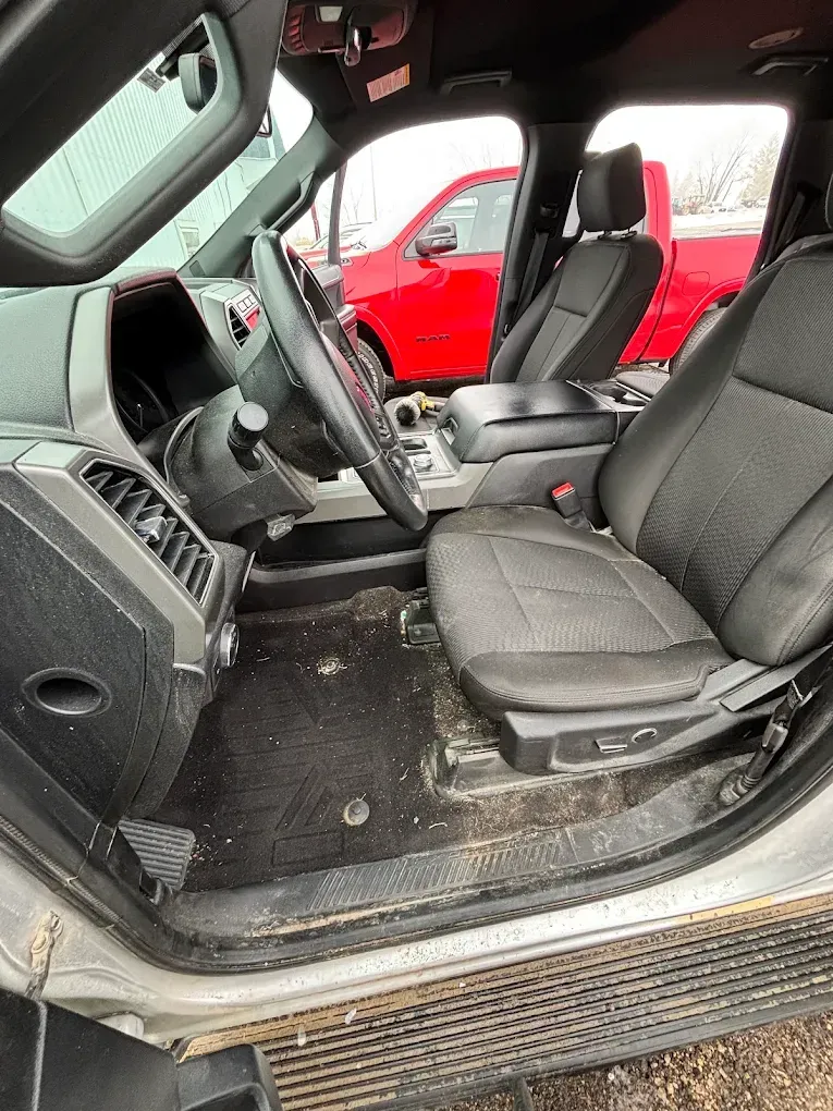 Interior of a pickup truck with black seats and red exterior visible through the open door.