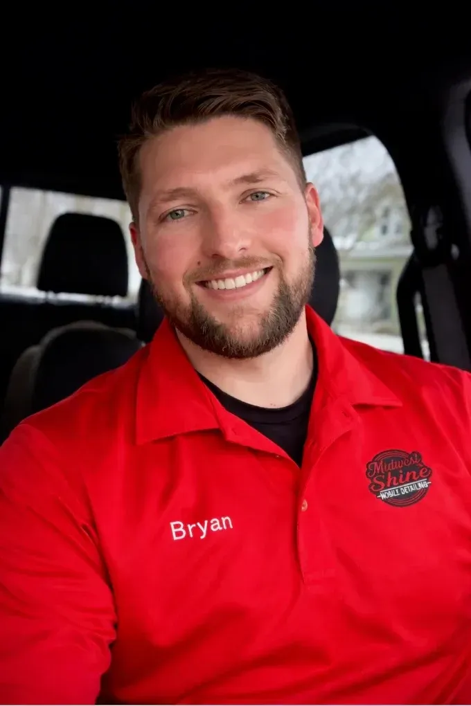 Smiling man in a red shirt seated in a vehicle interior