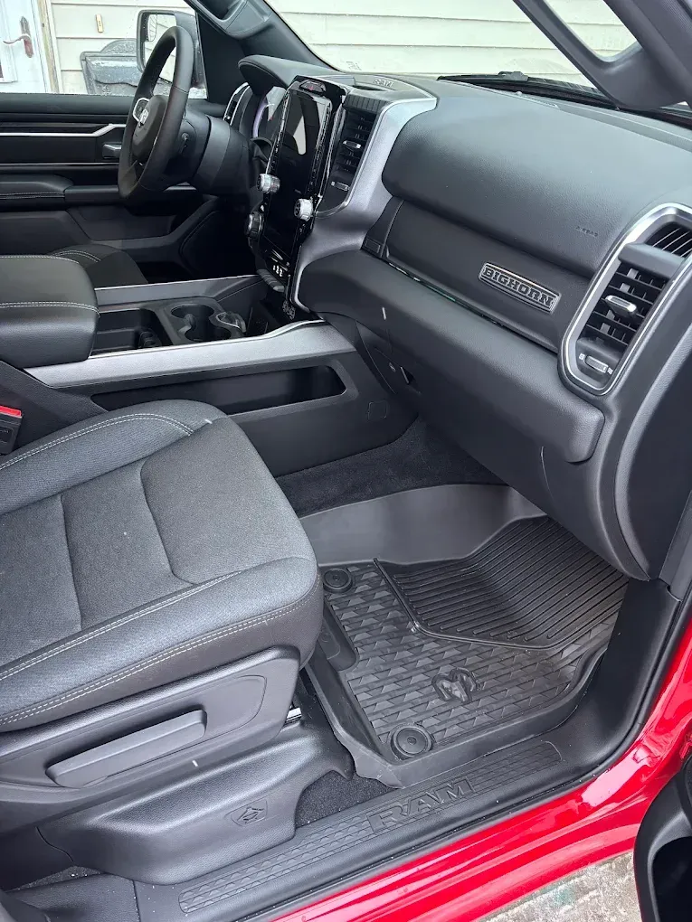 Car interior with black seats and dashboard, viewed from the open red passenger door