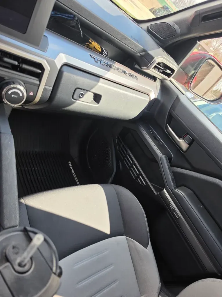 Car interior with dashboard, center console, and two-tone front seats in black and beige.