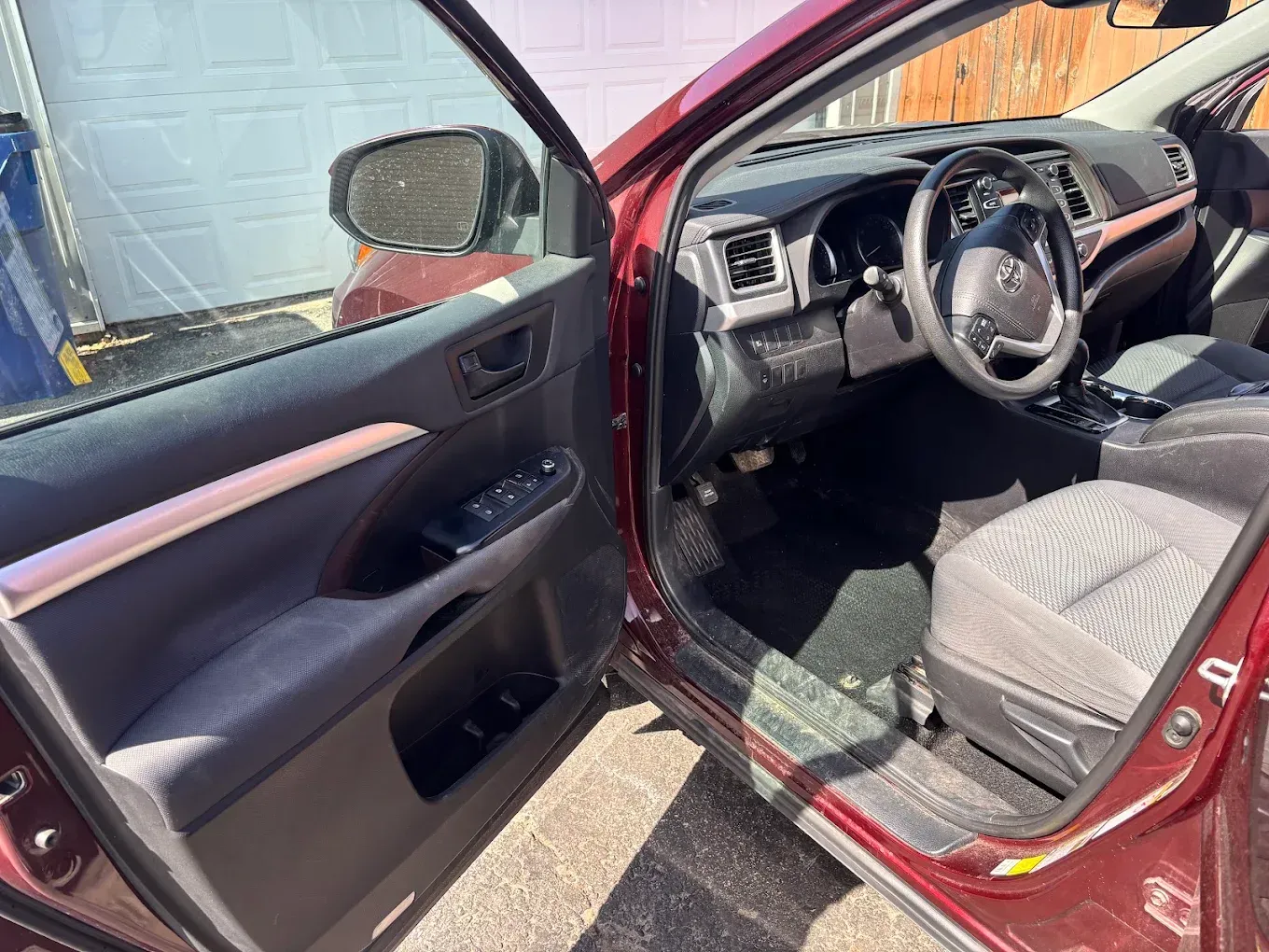 Open red car with driver door ajar, showing black interior and steering wheel.