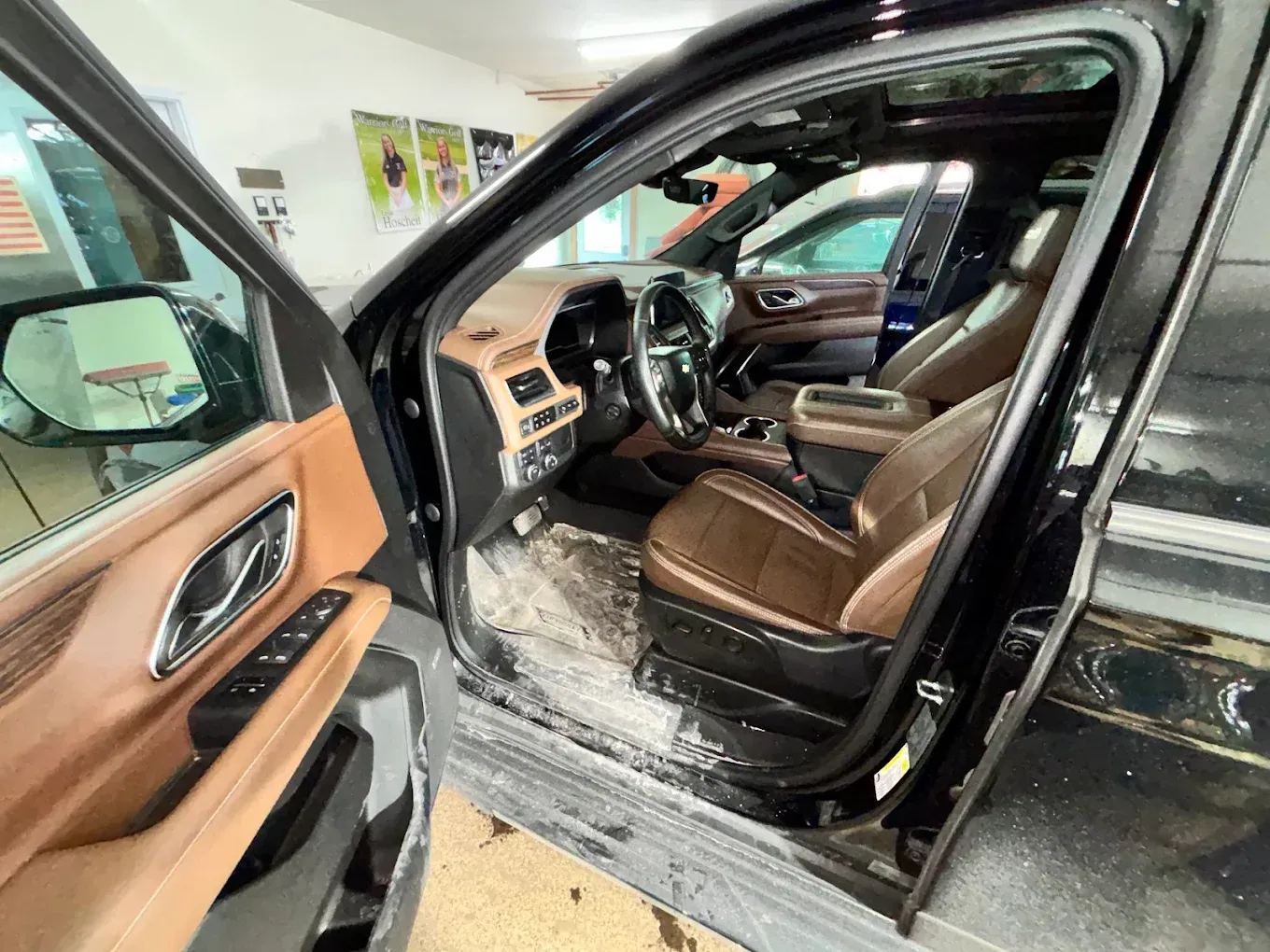 Open car door showing tan leather interior with snow on the floor and lower door sill