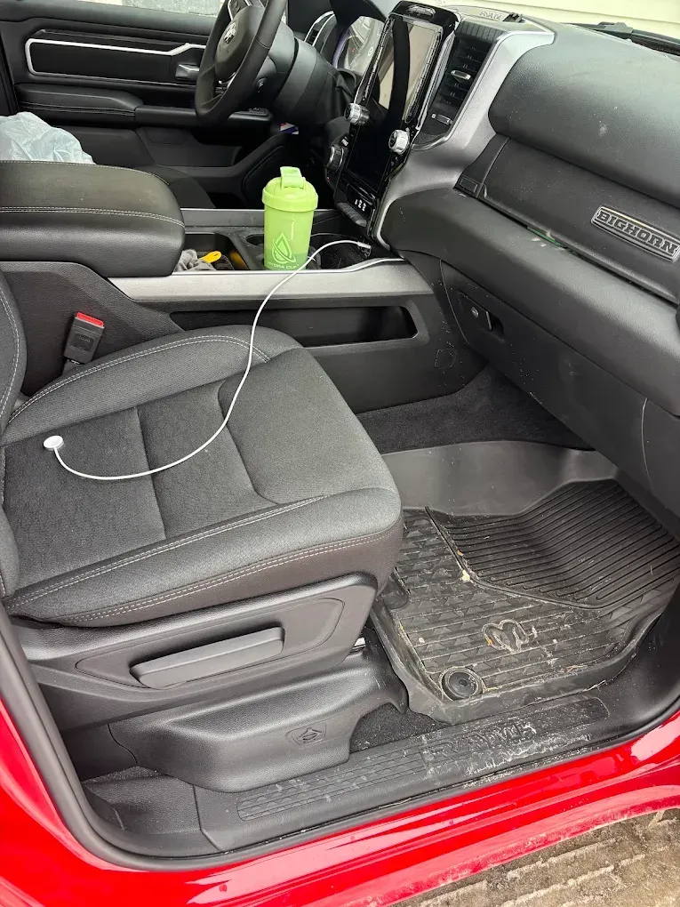 Red car interior with black seats, green bottle in center console, and white cable on the front seat