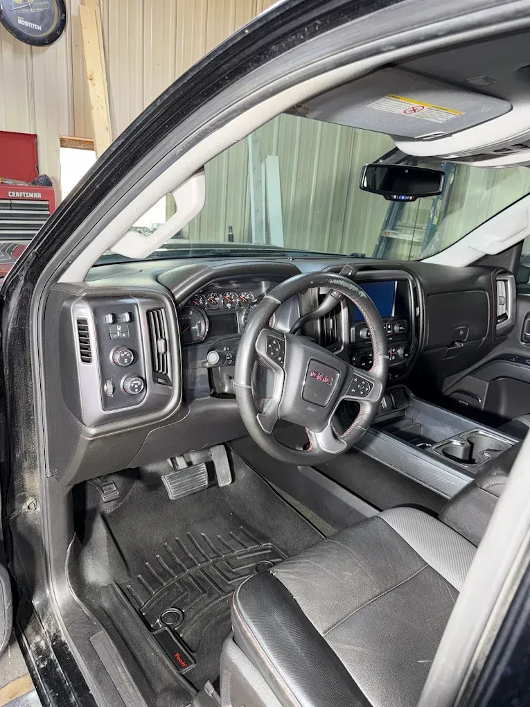 Modern GMC truck interior with black leather seats, steering wheel, and dashboard visible through the open driver’s door