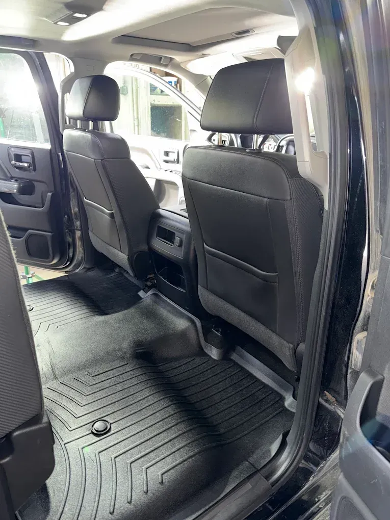 Interior of a van with two black front seats and rubber floor mats, view from the open side door