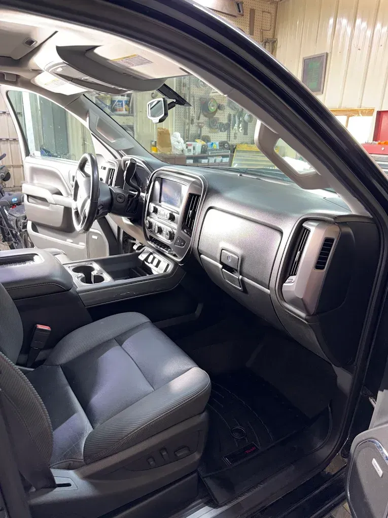 Truck interior with gray seats and dashboard, viewed through an open front door in a garage
