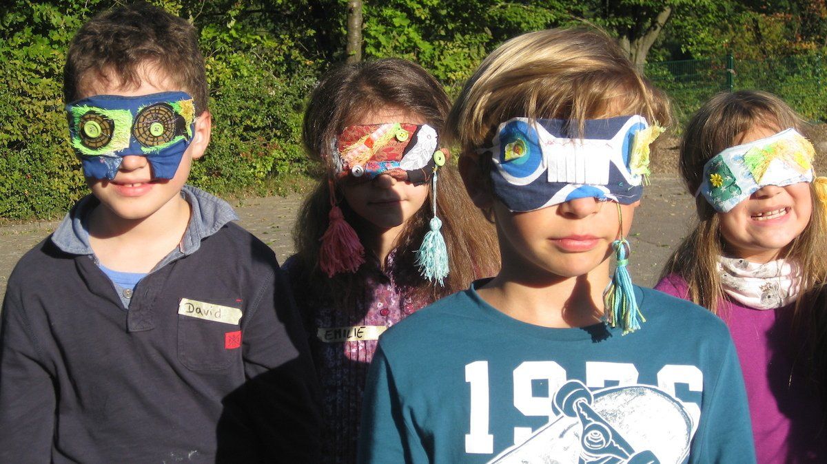 Vier Kinder mit bunten Schlafmasken stehen draußen und lächeln.