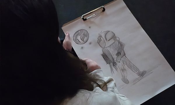 Eine Person zeichnet eine Karikatur eines Astronauten, der neben einem Planeten eine Laserpistole hält.