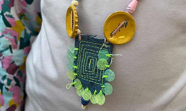 Halskette aus recycelten Materialien: Denim, Flaschenverschlüsse, Perlen und Pailletten.