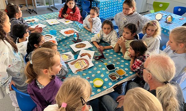 Kinder und Erwachsene versammelten sich um einen Tisch; ein Kunstprojekt war in Arbeit.
