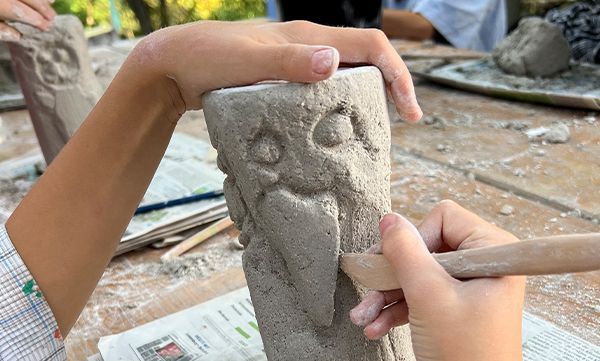 Eine Person benutzt ein Bildhauerwerkzeug, um Details in eine graue Betonform zu schnitzen.