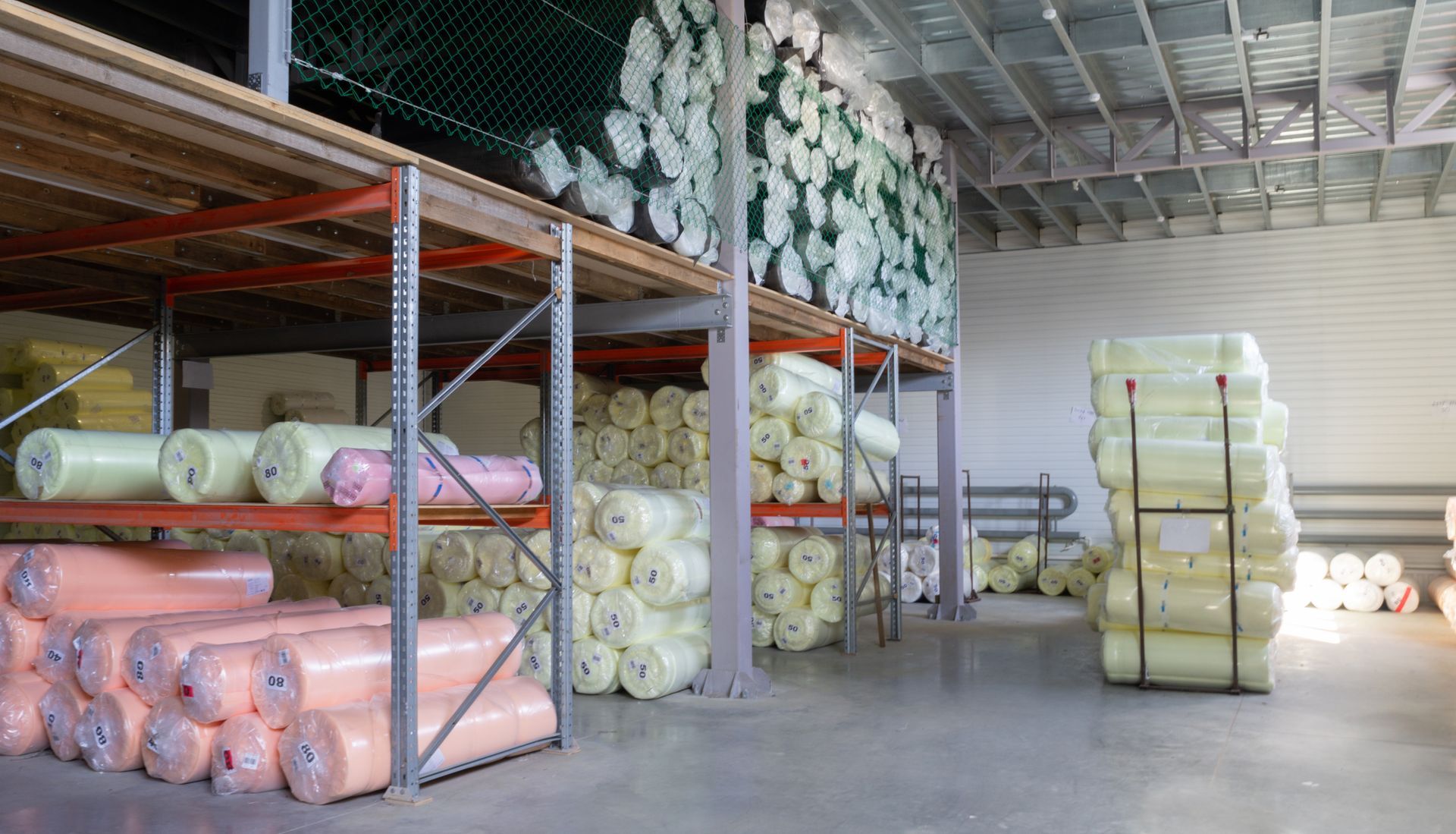 A large selection of fabric rolls on shelves in a furniture factory warehouse. A large selection of fabric rolls on shelves in a furniture factory warehouse.