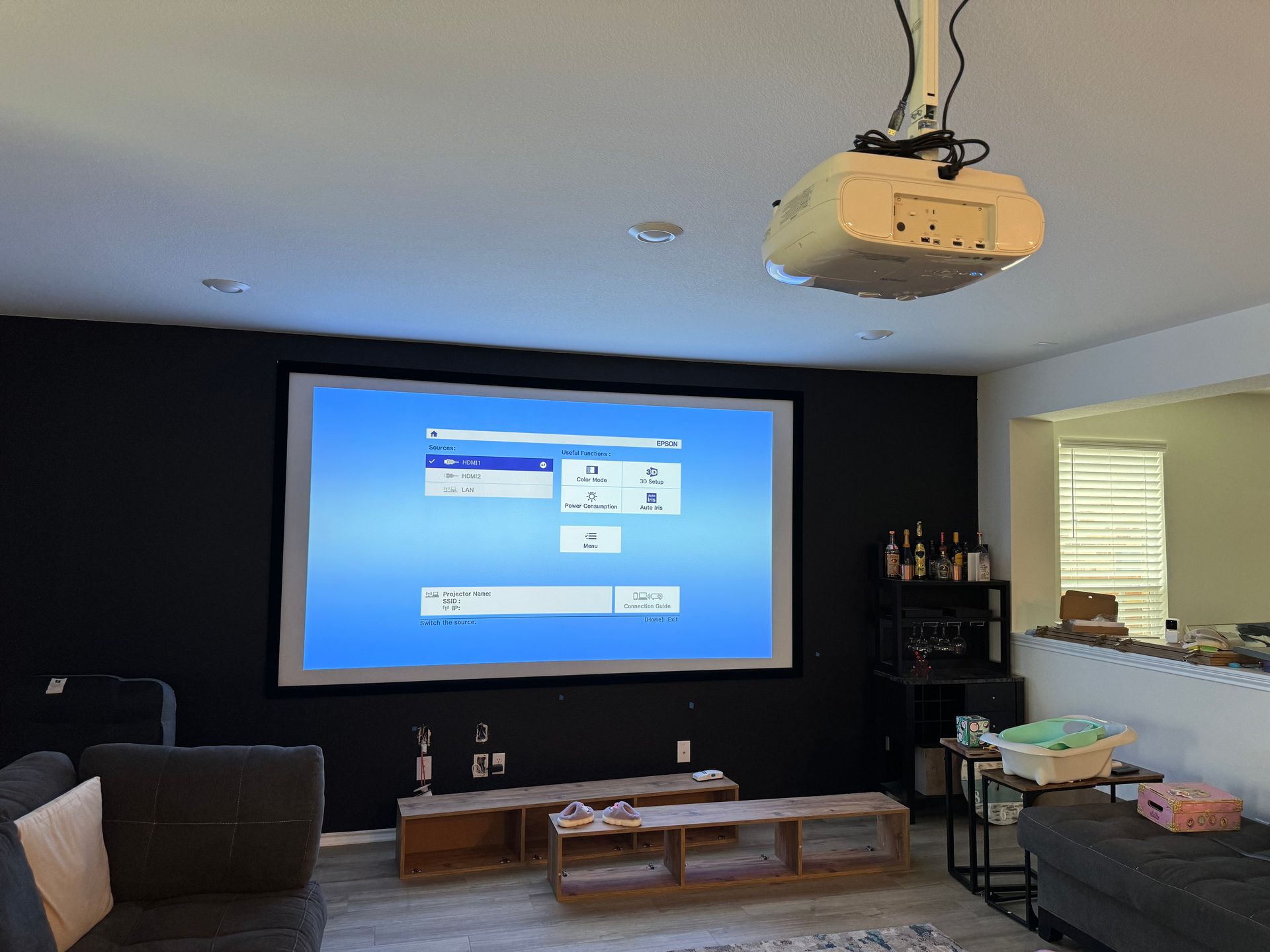 A living room with a projector screen hanging from the ceiling.