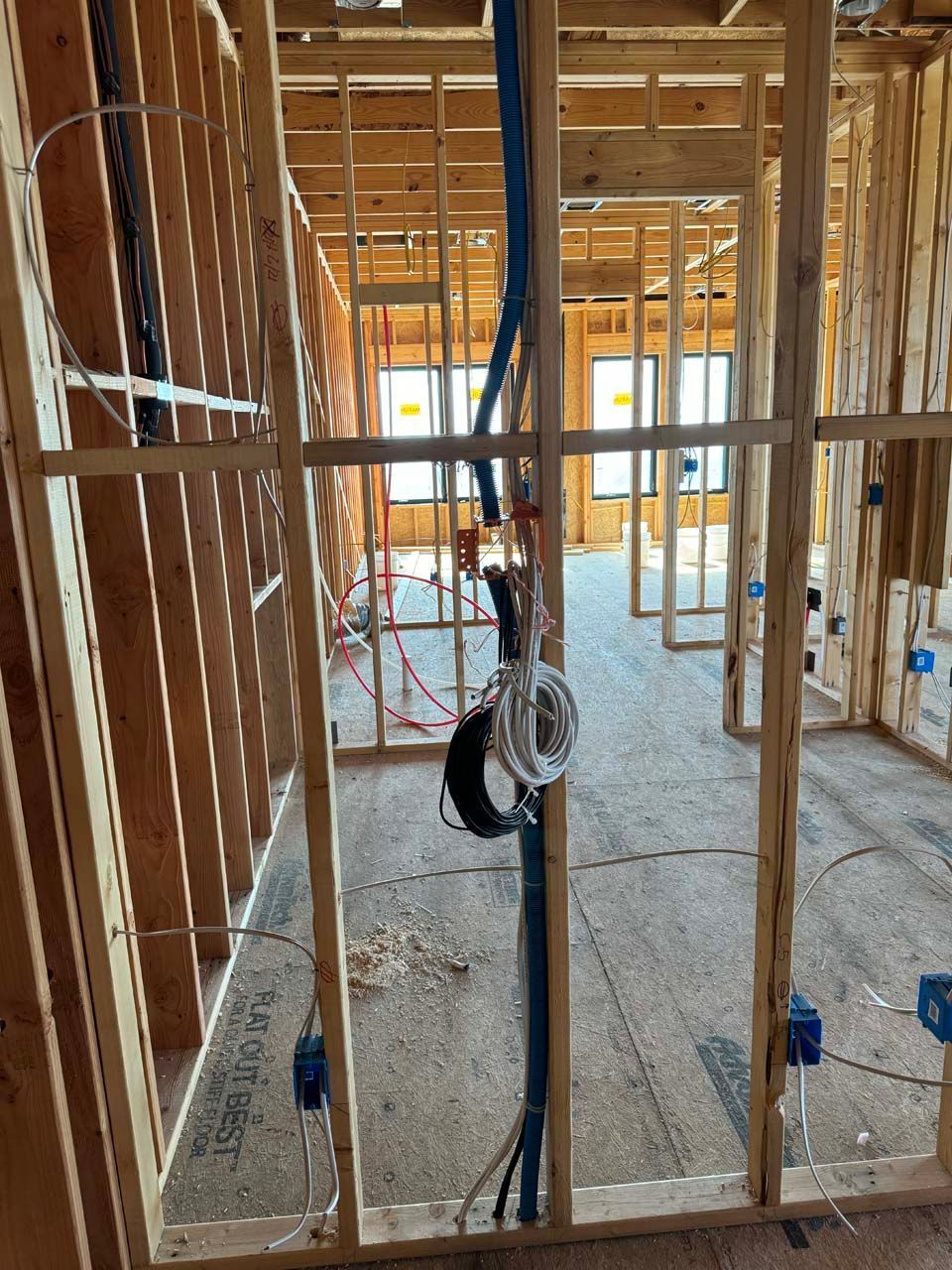 A room in a house under construction with a lot of wires hanging from the ceiling.