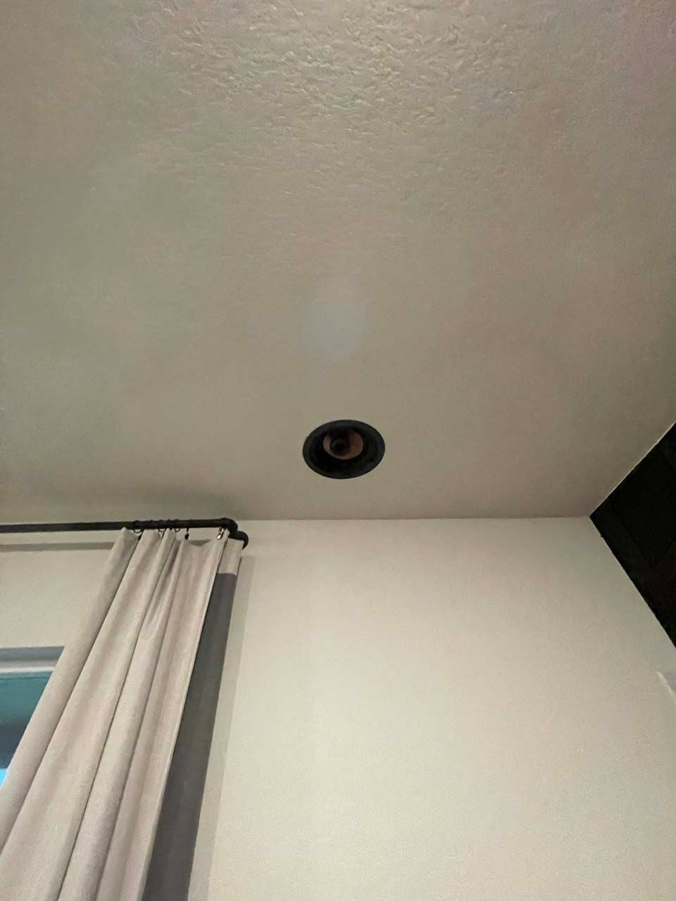 A room with a ceiling light and a window with curtains.