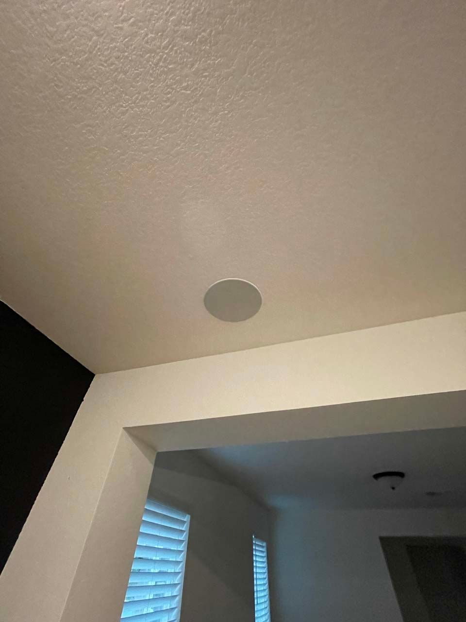 A ceiling speaker is hanging from the ceiling of a room.